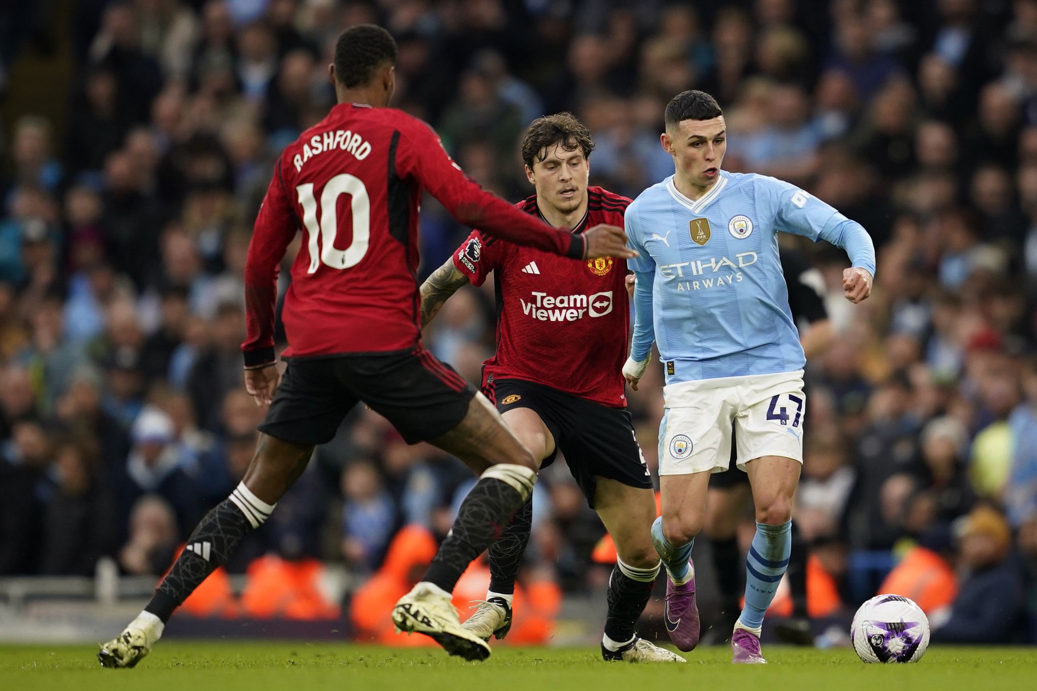 Phil Foden, right, controls the ball the ball as Manchester United's Marcus Rashford, left and Victor Lindelof challenge